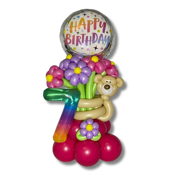 Bear Hug Birthday Flower Balloon Bouquet features an adorable bear holding pink and purple flowers, a 14 inch Rainbow Jelly Number balloon and a 17 inch Happy Birthday Foil Balloon.