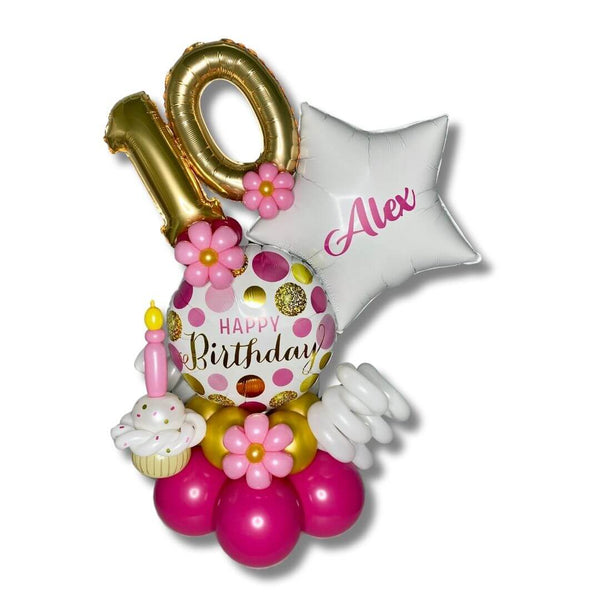 Pink & Gold Dots Birthday Balloon Marquee features 17 inch Happy Birthday foil balloon with pretty pink and gold dots, 14 inch gold number foil balloon, white star with custom name of recipient, balloon cupcake and flowers on a pink and gold balloon base.